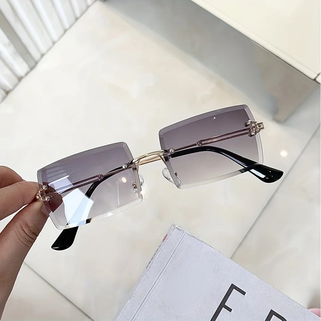 rimless, rectangular sunglasses with a brown gradient tint and decorative metal hinges.