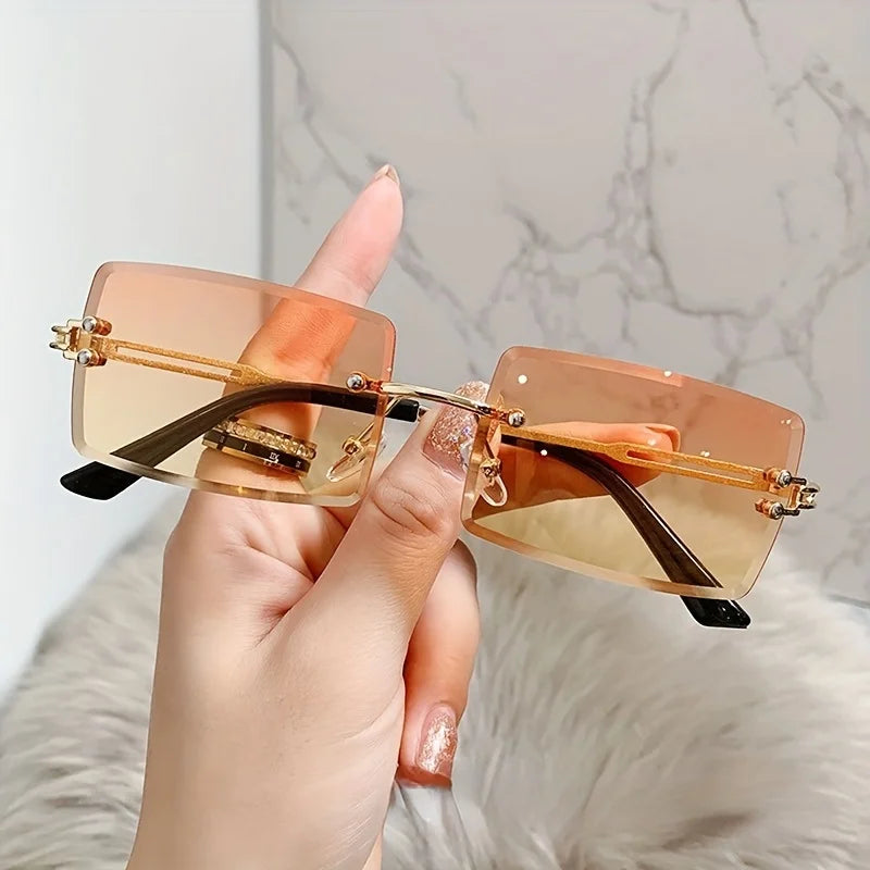 rimless, rectangular sunglasses with a brown gradient tint and decorative metal hinges.
